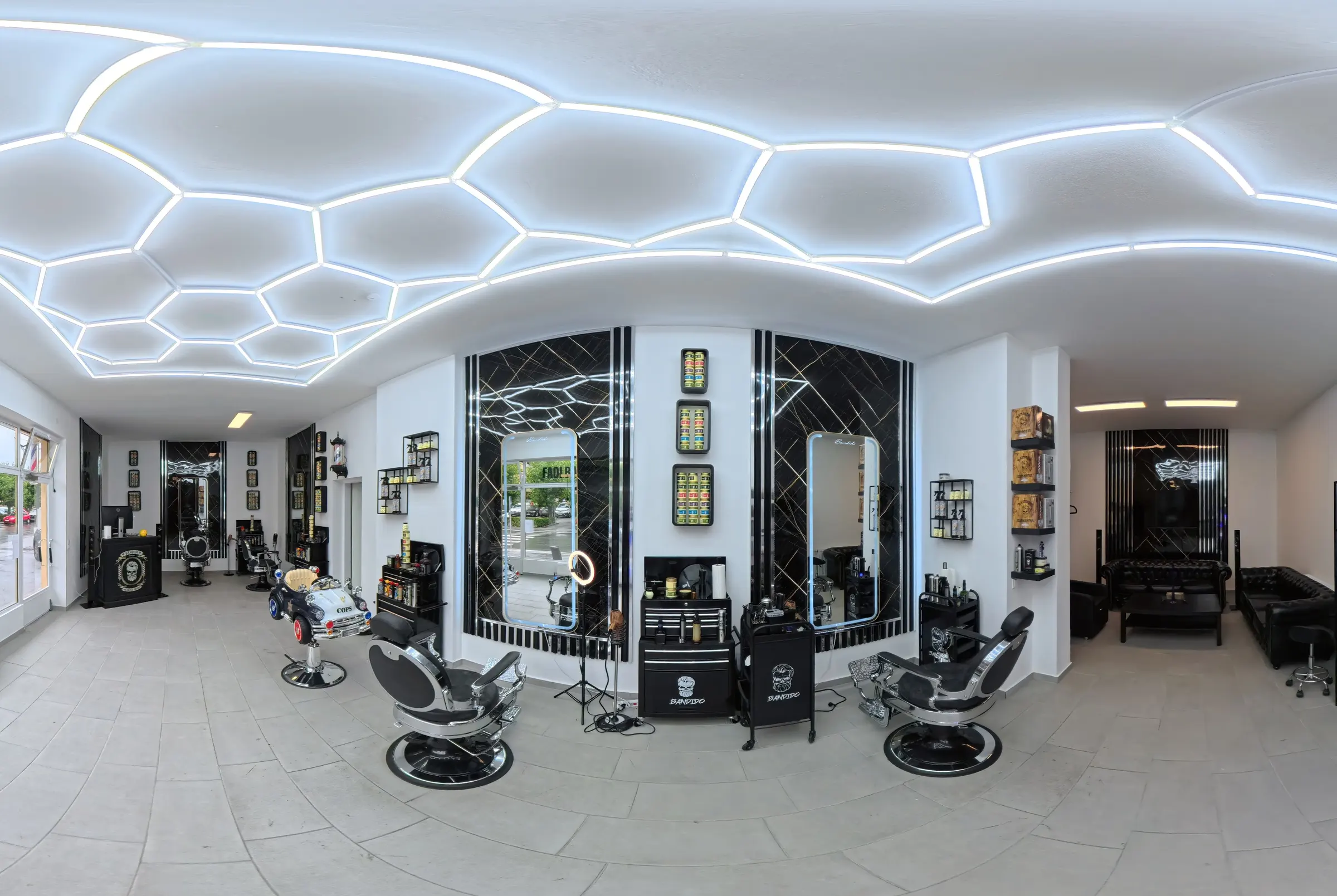 Der Salon von Fadi Barbershop: Wabenförmige LED-Decke, schwarze Marmorwände, Spiegel und verchromte Barberstühle