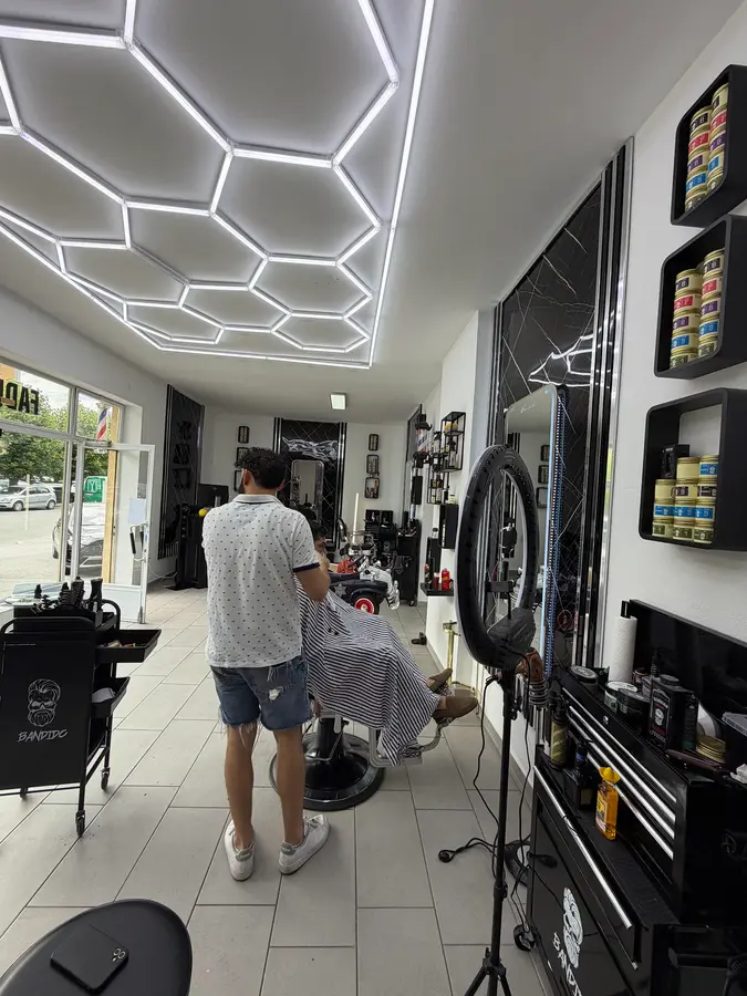 Ein Barbier schneidet einem Kunden die Haare unter der Waben-LED-Decke