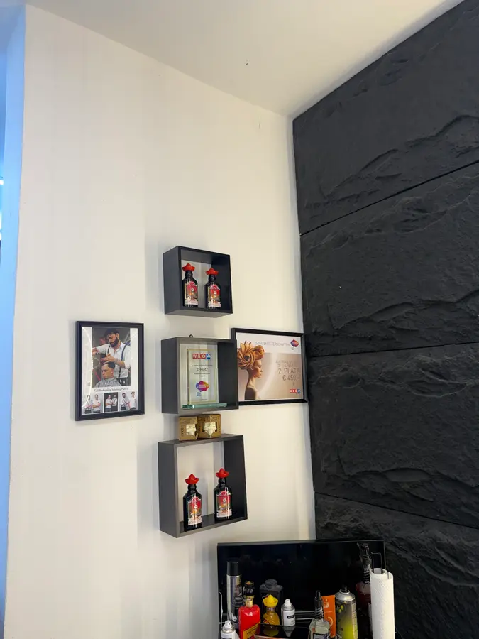 Weiße Wand mit Regalen, gerahmten Bildern und einer Wand aus schwarzem Stein