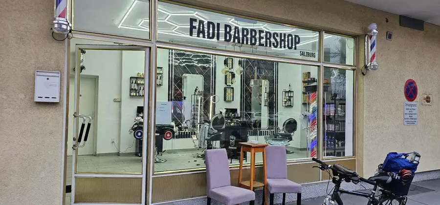 Schaufenster mit dem Schriftzug Fadi Barbershop Salzburg und zwei Barber-Poles